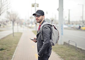 A fashionable young man in Budapest checking his smartphone on a busy street.